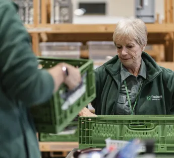 Foodbank volunteer carrying a crate.