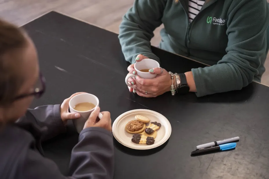 Two people having a cup of tea with some biscuits