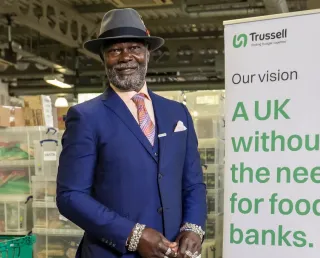 One of Trussell's Ambassadors, Levi Roots, standing by a sign sharing our vision of A UK without the need for food banks