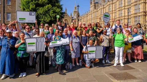 A group of people standing outside Westminster holding banners