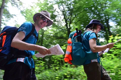 Two challenge participants with rucksacks, one looking at camera holding map