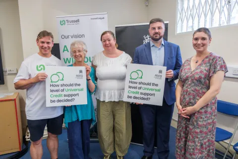 Five people holding signs asking how Universal Credit should be decided